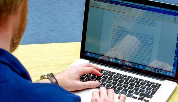 Man looking at a word document on a laptop