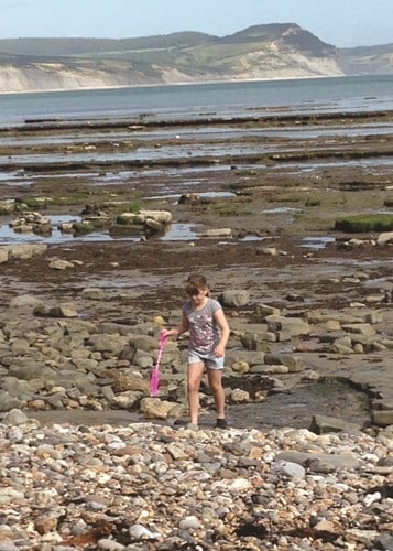 Deaf child on the beach with a spade