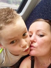 A young boy and his mum posing on a train.