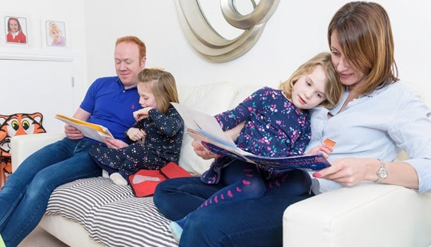 Jemima reading with her mum and her sister reading with their dad on the sofa.