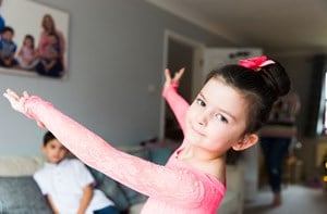 A girl shows off her ballet moves in her living room. 