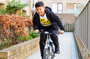 A deaf boy with hearing aids riding his bike. 
