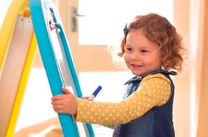 Young girl drawing on a whiteboard easel