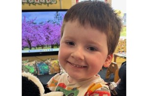Young boy holding a stuffed animal in a nursery setting